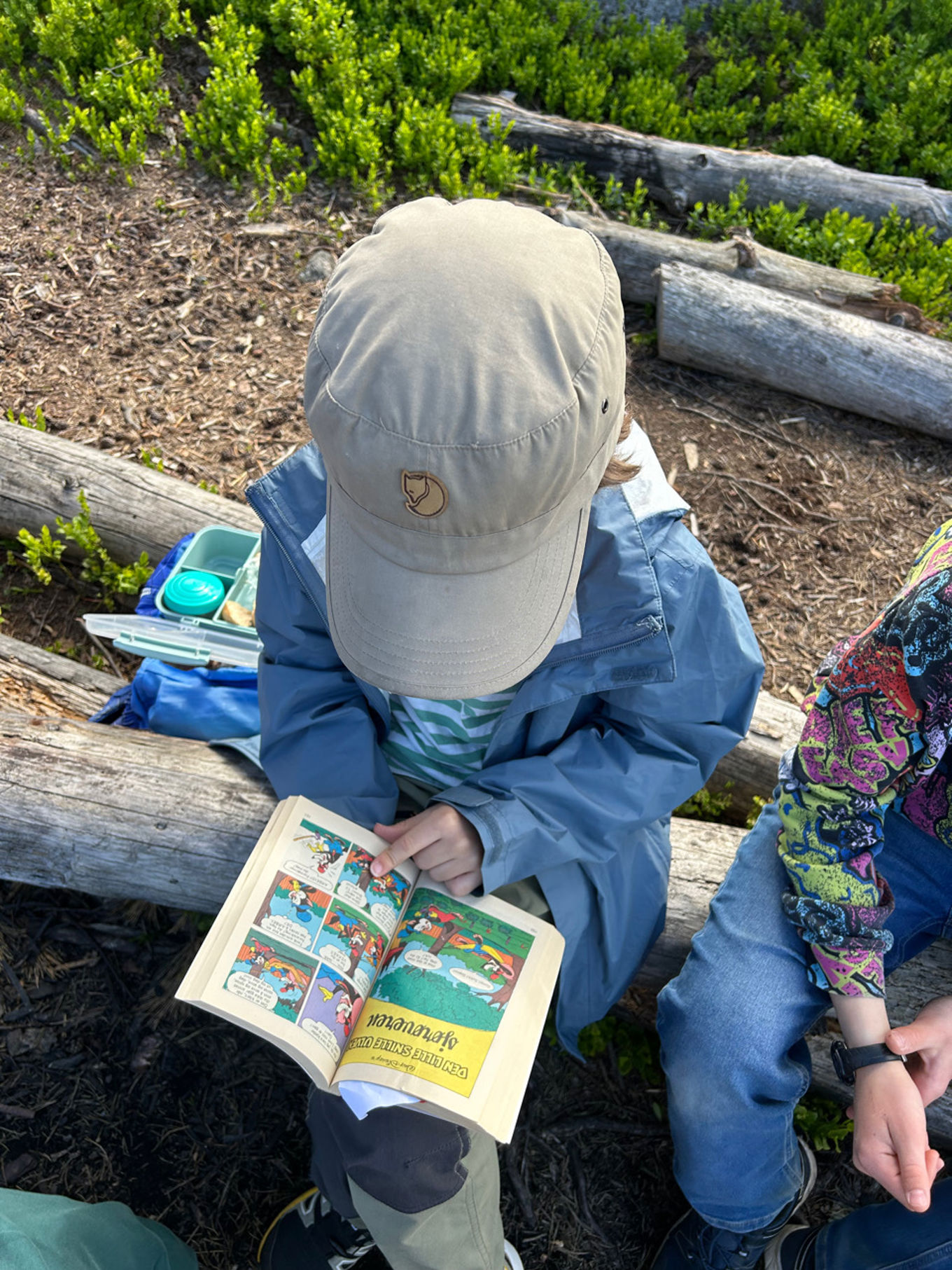 en person som sitter på bakken og leser en bok