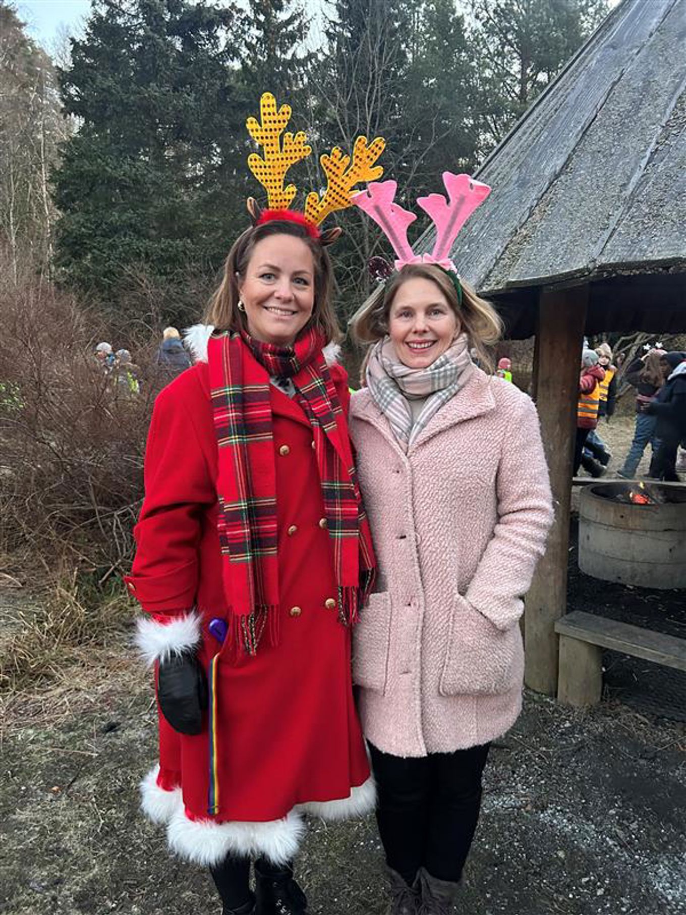 Foto: Camilla Tilrem Onstad to barnr iført røde frakker og står utenfor en bygning med et tre og et tak med en stjerne